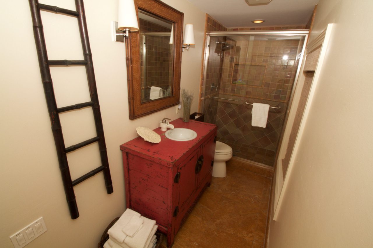 A bathroom with a red cabinet and toilet.
