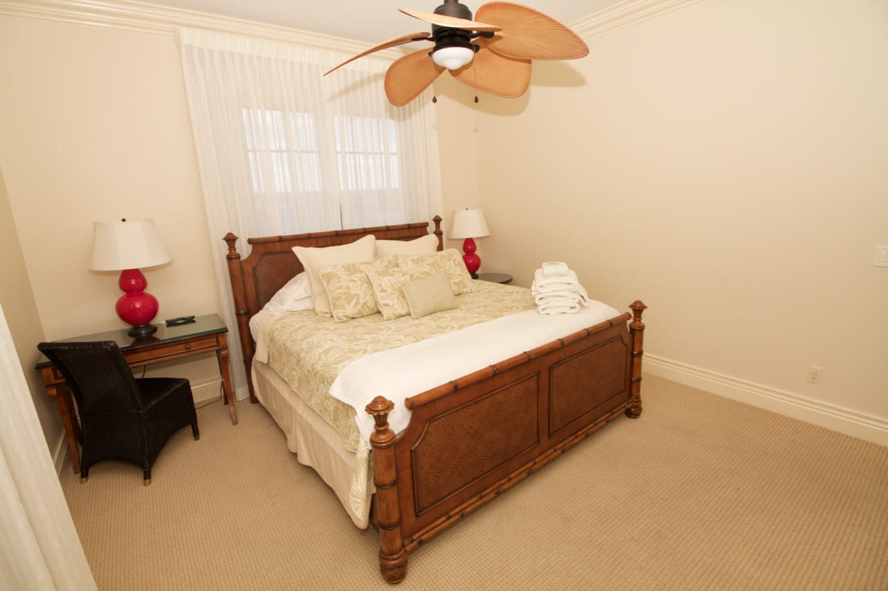 A bedroom with a bed, nightstand and ceiling fan.