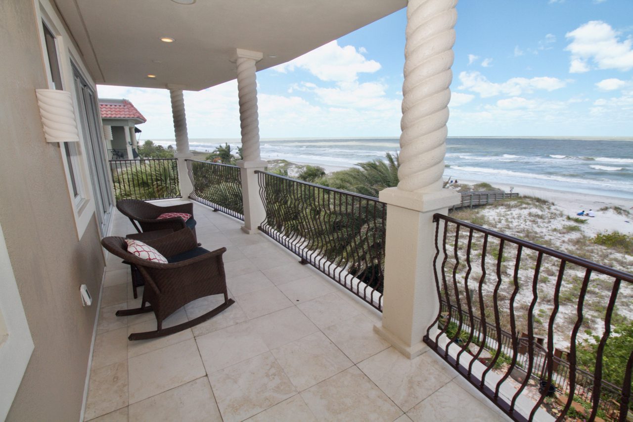 A porch with rocking chairs and a view of the ocean.